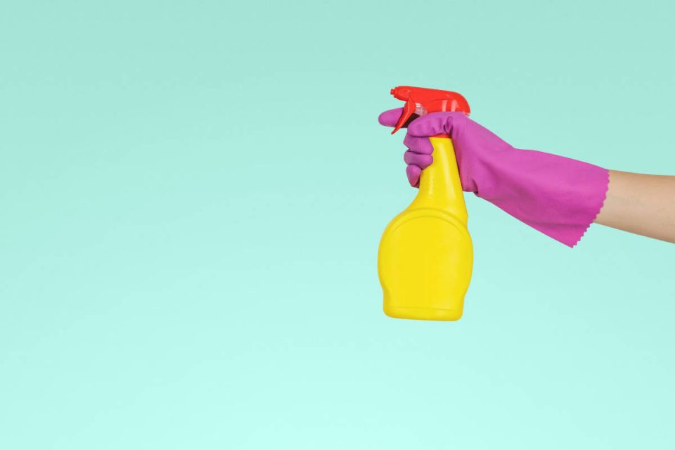 Reinigungsflasche in gelb vor türkisem Hindergrund