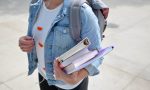 Frau trägt Rucksack und Bücher im Arm
