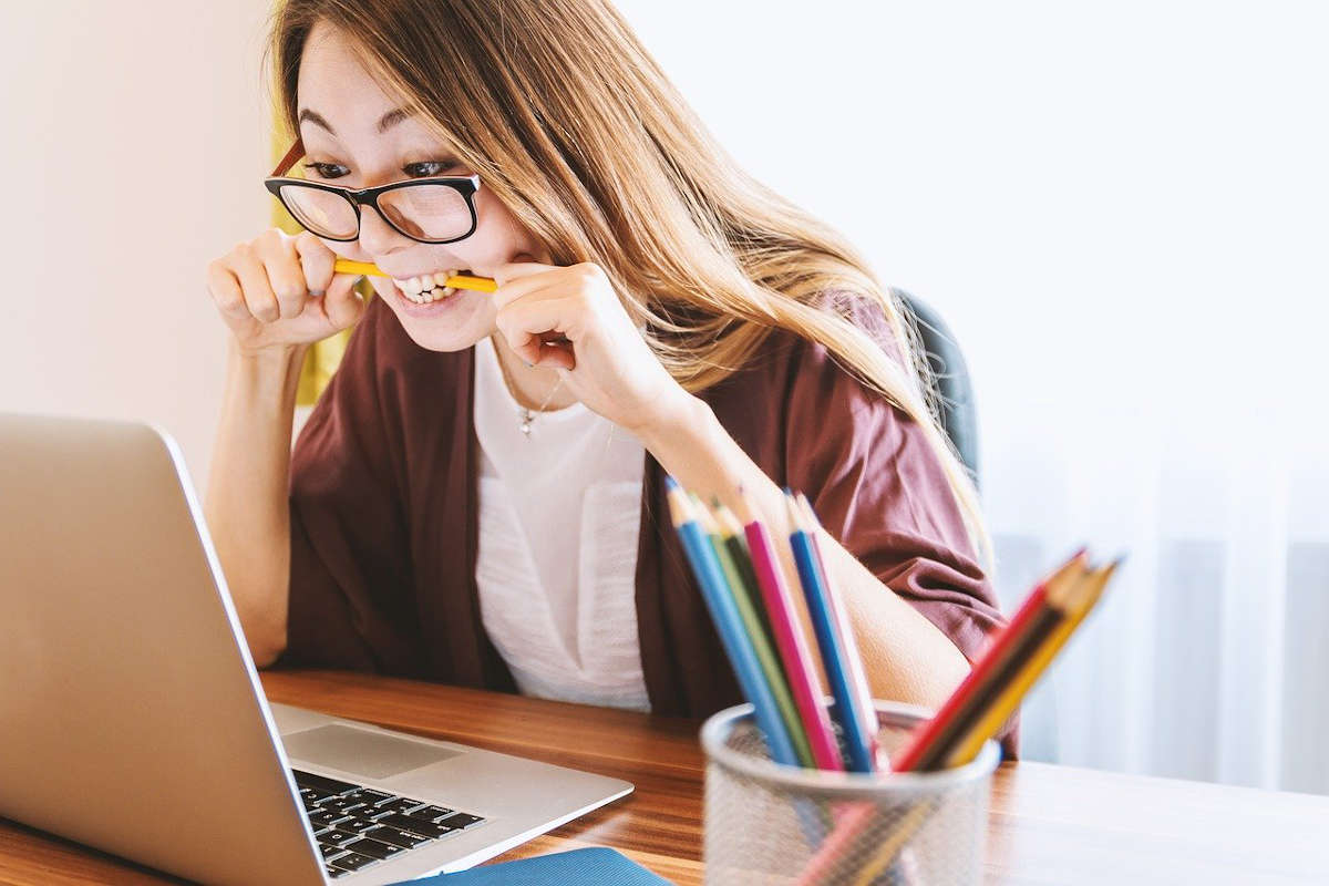 Junge Frau am Laptop kann sich nicht entscheiden